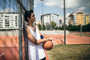 teen boy resting holding basketball